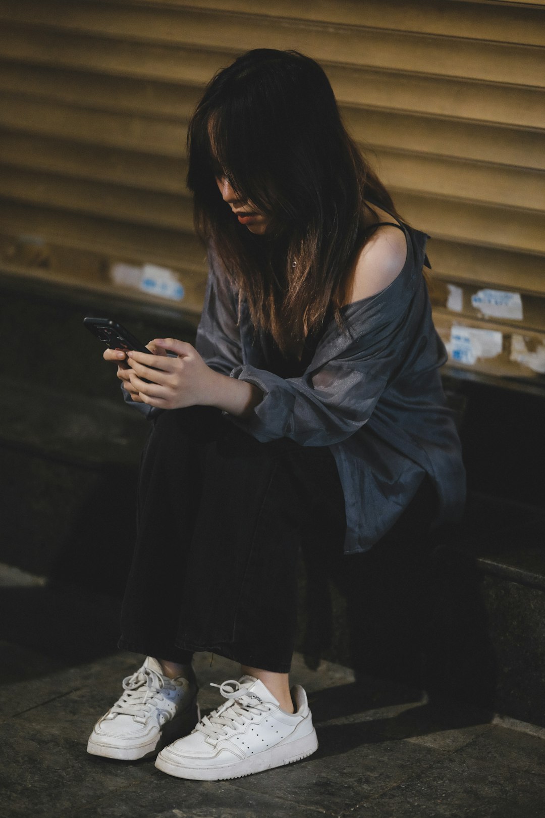 Foto von Nguyen Quan Eine Frau sitzt auf dem Boden und schaut auf ihr Handy.